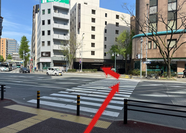 進んで行くとスクランブル交差点があり、横断歩道を右手に（渡った先はファミリーマート）渡ります。渡った先を左方向の横断歩道を渡りTOYO　HOTEL側へ渡り（画像右方向）へ進みます。